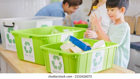 Authentic Shot Of Real Asian Parents Are Teaching Kid How To Recycle Help The Boy Aware Environmental Importance - Boy Hold A Plastic Bottle With Trash Containers On Table