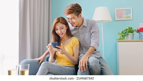 Authentic Shot Of Real Asian Young Couple Smile Use Smartphone Surf The Net Watch Content Have Fun Together