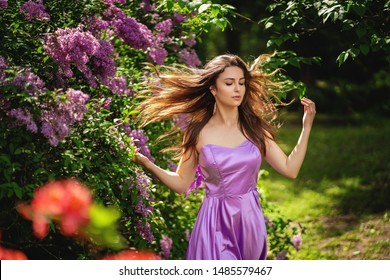 Authentic Woman Near A Blossoming Lilac Tree. Her Hair Flutters In The Wind