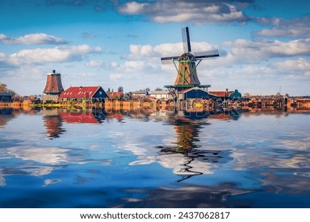 Authentic Zaandam lighthouse and windmills reflected in the calm waters of popular Dutch channels in Zaanstad willage. Calm spring scene of Zaanse Schans, Netherlands, Europe. Travel the world.