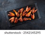 Authentical barbecue chicken wings and drumsticks with hot chili sauce as marinade served as top view on a rustic grill grate