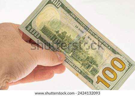 Authentication of banknote 100 dollars for clearance. Watermarks on a 100-dollar bill. Banknote in hand on a white background with a watermark. Franklin watermark on 100 bill