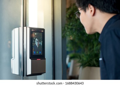 Authentication by facial recognition concept. Biometric admittance control device for security system. Asian man using face scanner to unlock glass door in office building. - Shutterstock ID 1688430643