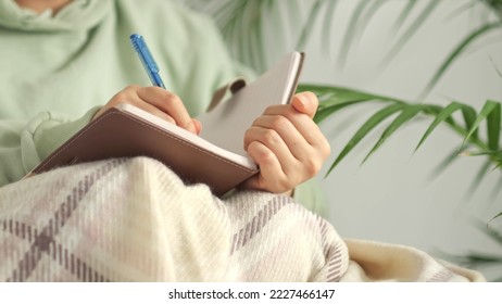 author scribbles notes in a notebook. young woman with pencil writing to diary at cozy home note. Scandinavian style, hygge concept. break from burnout and digital overload