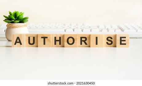 authorise word made with wooden blocks. front view concepts, green plant in a flower vase and white keyboard on background