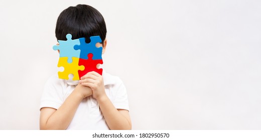 Autism awareness day April 2 - Studio Portrait of a little cute asian child cover his face with the colorful puzzles pieces. Autism Spectrum Disorder concept, ASD, Syndrome, Symptoms, Copy space - Powered by Shutterstock