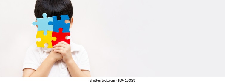 Autism awareness day April 2 - Studio Portrait of a little cute asian child cover his face with the colorful puzzles pieces. Autism Spectrum Disorder concept, ASD, Autistic Syndrome, Symptoms, Banner. - Powered by Shutterstock