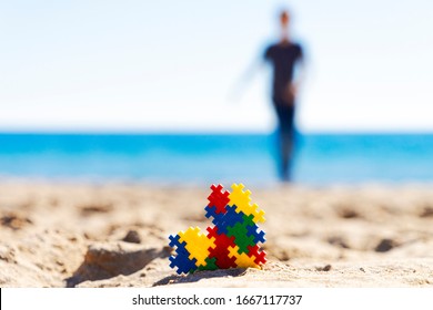 Autism awareness day concept. Colorful puzzle autism awareness heart on beach sand and silhouette of autistic kid boy - Powered by Shutterstock