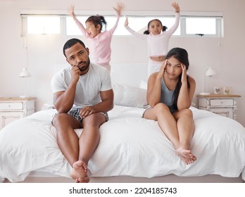 Autism, Headache And Children With Tired Parents In Their Bedroom At Home With Adhd Kids Jumping On The Bed. Family, Noise And Stress With A Sad Man And Woman Looking Exhausted With No Energy