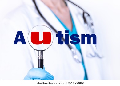 AUTISM Text Is Written On The Background Of A Doctor Holding A Magnifying Glass. Medical Concept.