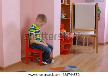 autistic boy. The child sits in the corner. Punished child. Frustrated, thoughtful boy