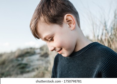 Autistic Boy Sitting In Sand Dunes Looking Down Shy