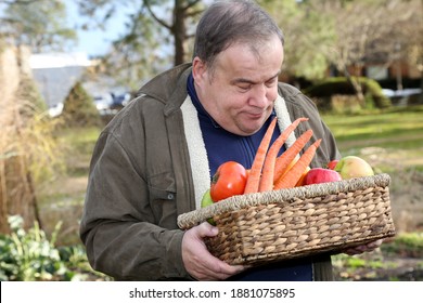 Autistic man working in the garden holding basket full of fruits and vegetables