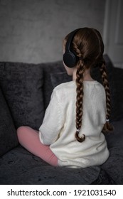 Autistic spectrum young girl sat quiet and alone with autism looking away back turned and headphones on to block out noise