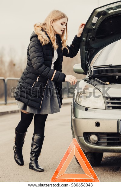 Auto assistance and insurance, troubles while
traveling concept. Broken car and auto triangle on road, woman
waiting for help.