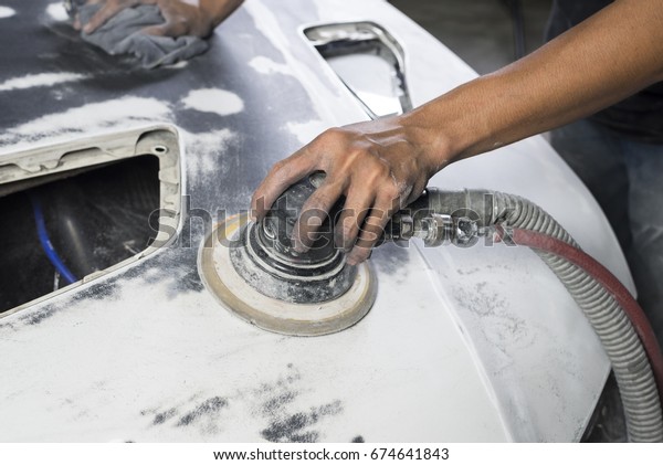 Auto body repair series: Closeup of mechanic\
sanding car bonnet