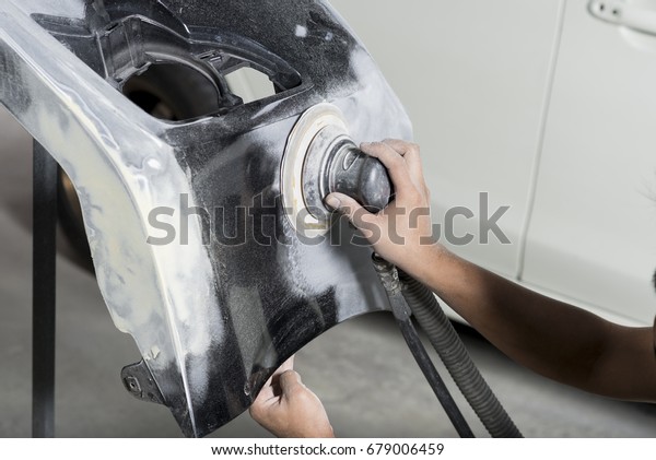Auto body repair series: Closeup of mechanic\
sanding car bumper