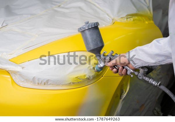 Auto body repair series: Mechanic painting yellow\
sports car