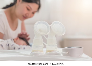 Auto breast pump machine, mothers breast milk is the most healthy food for newborn baby. Happy Asian mother with baby at background