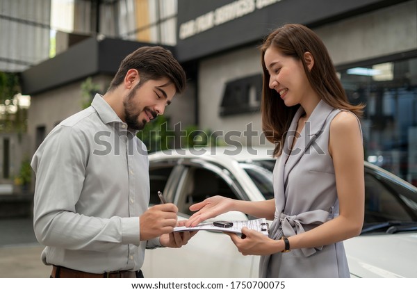 Auto business, car sale, consumerism and people\
concept - woman Sign Contract with car dealer in auto show. car\
salesman is making deal with lender. Used cars cheaper than new\
cars. But to buy a used