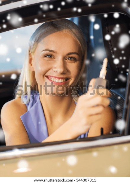 auto business, car sale, consumerism and people\
concept - happy woman taking car key from dealer in auto show or\
salon over snow effect