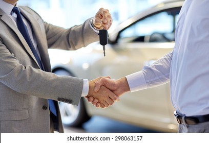 auto business, car sale, deal, gesture and people concept - close up of dealer giving key to new owner and shaking hands in auto show or salon - Shutterstock ID 298063157