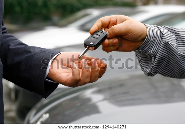 auto business, car sale, deal, gesture\
and people concept - close up of dealer giving key\
