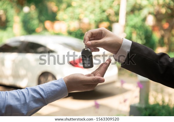 auto business, car sale, deal, gesture\
and people concept - close up of dealer giving\
key.