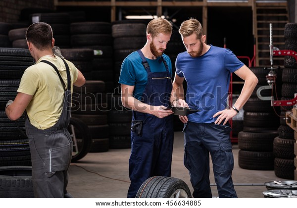 Auto business, car sale,\
deal, gesture and people concept: men looking to clipboard in car\
service.
