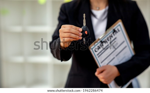 Auto business, car sale, gesture and people concept -\
close up of business woman or salesman with documents giving car\
key ,