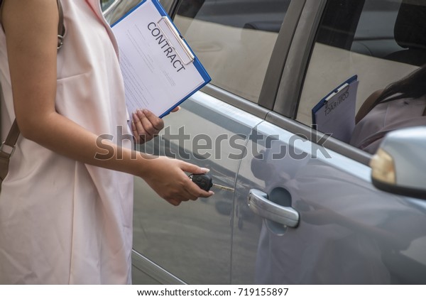 Auto business, car sale, Car rental consumerism and\
people concept -  woman Turn key    and holding Contract with car\
dealer in auto show