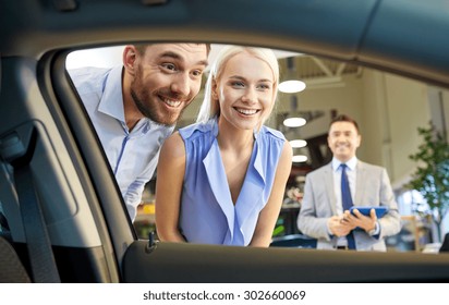 Auto Business, Car Sale, Technology And People Concept - Happy Couple With Car Dealer In Auto Show Or Salon