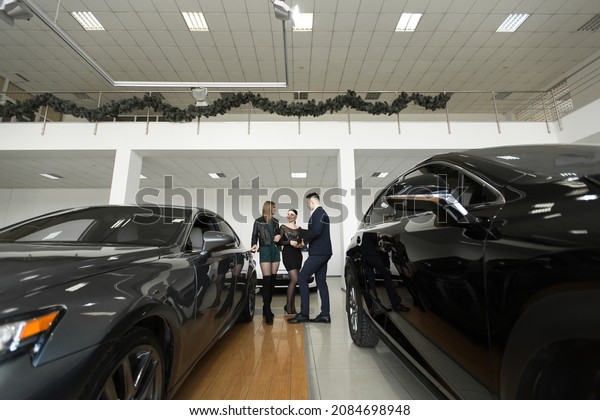 Auto business,
car sales - a couple of friends of girls with a car dealer choose a
car in a car dealership