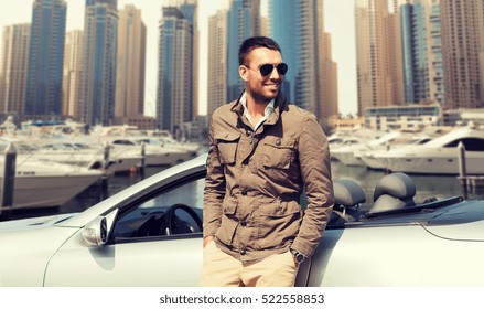 auto business, transport, leisure and people concept - happy man near cabriolet car over dubai city port background
