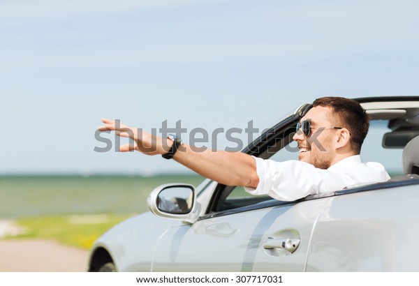 auto business,\
transport, leisure and people concept - happy man driving cabriolet\
car and waving hand\
outdoors