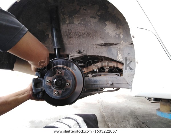 Auto car is lifted on a lift with the wheels removed in\
a car service. View of the rear suspension of the car. Brake system\
of the car.  