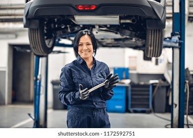 Auto Car Repair Service Center. Happy Female Mechanic Standing By The Car