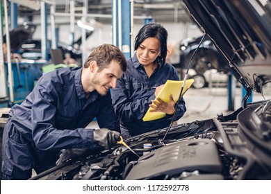 Auto car repair service center. Two mechanics - man and woman examining car engine