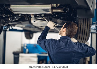 Auto Car Repair Service Center. Mechanic Examining Car Suspension