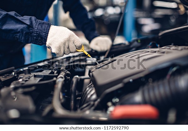 Auto car repair service center. Mechanic checking\
engine oil level