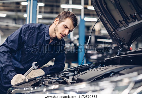 Auto car repair service center. Mechanic examining
car engine