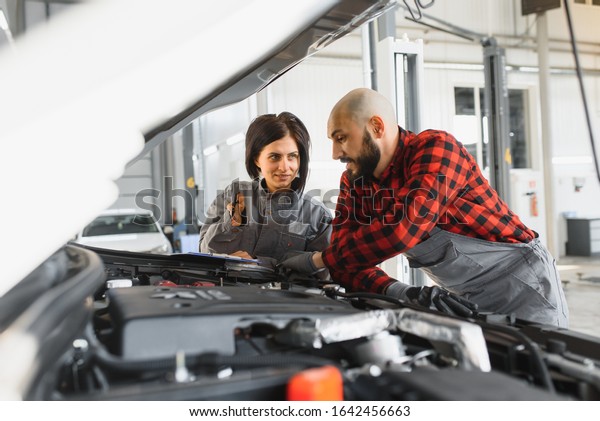 Auto car\
repair service center. Mechanic examining car engine. Female\
Mechanic working in her workshop. Auto Service Business Concept.\
Pro Car female Mechanic Taking Care of\
Vehicle.
