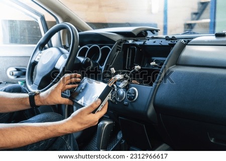 Auto in Car Service, process of installing modern 2-din radio sound system. Auto electric hands on dashboard fixing problem close-up