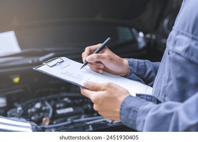 Auto check, car service shop concept. Automobile repairman writing job checklist on clipboard, mechanic checking engine to estimate repair machine, inspecting maintenance by engineer at vehicle garage - Powered by Shutterstock