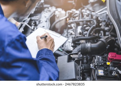 Auto check, car service shop concept. Automobile repairman writing job checklist on clipboard, mechanic checking engine to estimate repair machine, inspecting maintenance by engineer at vehicle garage - Powered by Shutterstock