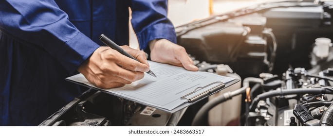 Auto check up and car service shop concept. Mechanic writing job checklist to clipboard to estimate repair quotation to client at workshop garage. - Powered by Shutterstock