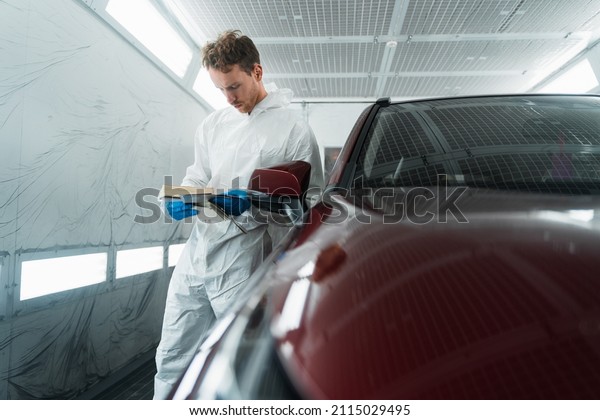 Auto colorist in the painting chamber
selects the color of the car paint with
samples