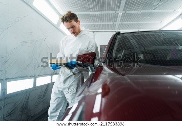 Auto colorist in the painting chamber\
selects the color of the car paint with\
samples