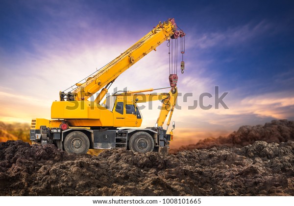 Auto crane on the ground at construction site\
with sunset background