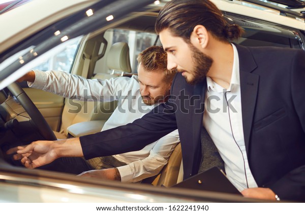 Auto dealer shows a new\
car to a man